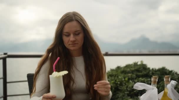 若い女性が海で山のレストランでカクテルを飲む — ストック動画