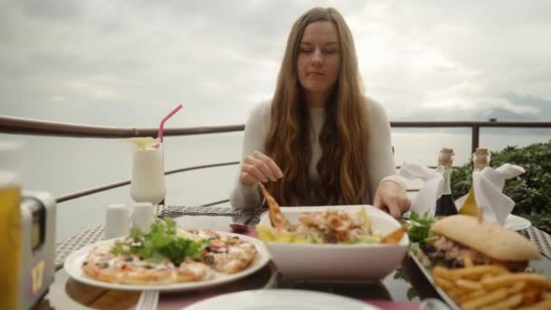 一位年轻女子在海边山上的一家餐馆里 拿着一片黄瓜和面包 — 图库视频影像