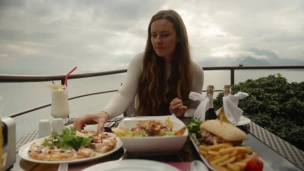 在海边的山上餐厅 这个年轻的女人吃了一片披萨 — 图库视频影像