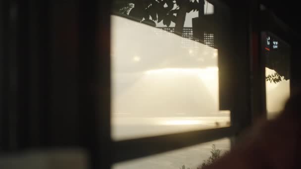 海によるレストラン 窓の外の山々 水の上の太陽の光線 若い女性は窓に座って海を見ます — ストック動画