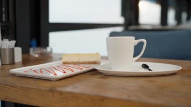 Tabakta çilek soslu limonlu cheesecake ve sıcak içecekli kupa, sıcak olandan buhar geliyor..