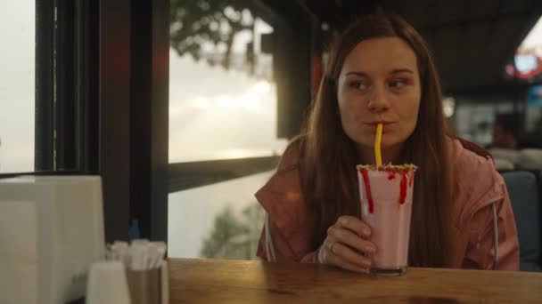 Genç Bir Kadın Pipetle Çilekli Milkshake Içiyor Bir Kafede Ceketle — Stok video