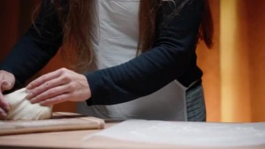 Uzun saçlı genç bir kadın pizza pişirir, masaya un serper ve ovalar..