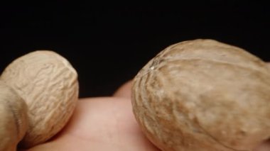 Elimde hindistan cevizi var, avucumun içinde döndürüyorum, siyah bir arka planda, makro.