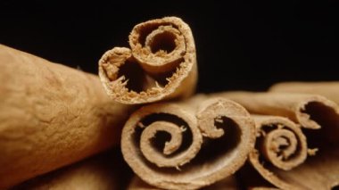 Siyah arka planda bir avuç kurutulmuş tarçın çubuğu. Dolly kaydırıcı aşırı yakın çekim