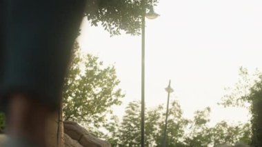 Aşağıdaki kamera, parkta düşen yaprakların arasında yürüyen genç bir kadının fotoğraflarını çekiyor. Parlak günbatımı güneşi önümüzde. Yakın plan. Yavaş çekim