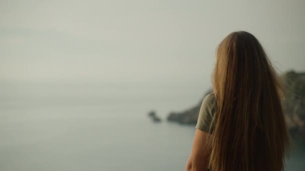 Молода Жінка Сонцезахисних Окулярах Краю Скелі Дивиться Море Захід Сонця — стокове відео