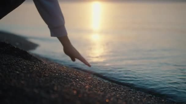 日出了 太阳已经接近水了 那位年轻妇女用手触摸着水 水面上的阳光和光芒 — 图库视频影像