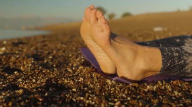 Sabahın erken saatlerinde sahilde çıplak ayaklı genç bir kadın. Yakın plan. Paspasın üzerinde yatıyor..