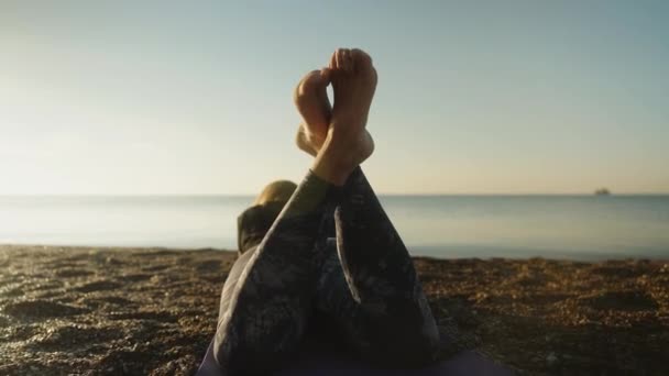 一位穿着紧身裤的年轻女子躺在海滨 双腿抬起来 相机慢慢地穿过她的身体 滑过她的身体 — 图库视频影像