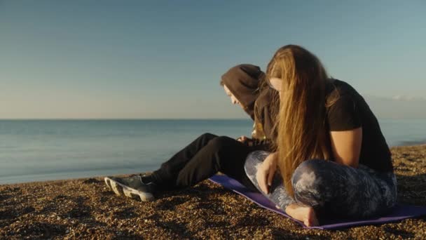 一对年轻夫妇在海滨遇见了日出 一个女孩把鹅卵石送给一个男人 他把鹅卵石扔进了海里 — 图库视频影像