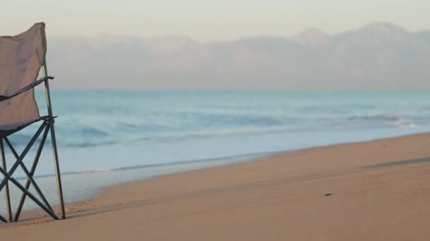 サンディー海のビーチに折り畳まれた青い椅子 山は残っています パノラマ — ストック動画