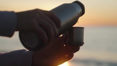 Denizde gün doğumuyla karşılaşırız. Metal bir termostan sıcak çay döküyorum. Yakın çekim, sıcak bir buhar.