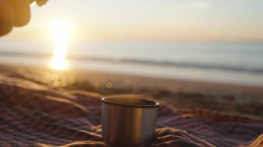 Deniz kıyısında gün doğumu. Sıcak çayı termostan metal bardağa döküyorum, battaniyeye..