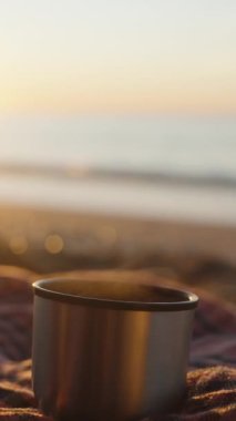 Deniz kıyısında gün doğumu. Sıcak çayı termostan metal bardağa döküyorum, battaniyeye..