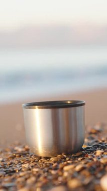 Deniz kıyısında sabah serinliği. Termostan metal bardağa sıcak içecek dolduruyorum. Ağır çekim. Dikey video Sosyal Ortamı