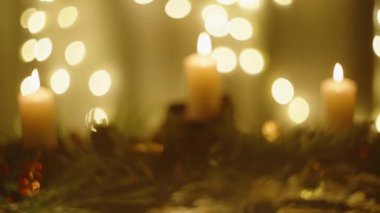 Görüntü yavaş yavaş odak noktasına gelir, süsler ve mumlarla Noel kurulumunda yavaşça keskinleşir..