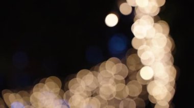 Bokeh, gece geç saatlerde ağaçlarda asılı duran yeni yıl çelenklerinden daireler çiziyor. Odaklanamayan resim.