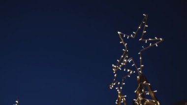 İki yeni yıl yıldızı, karanlık gökyüzünde parlayan ışıkların altında parıldıyor..