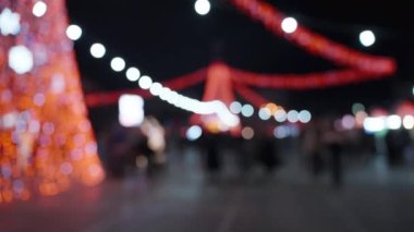 Odak dışı görüntü, Noel akşamı pazarı, kalabalık ve renkli çelenkler her yerde. Bokeh.