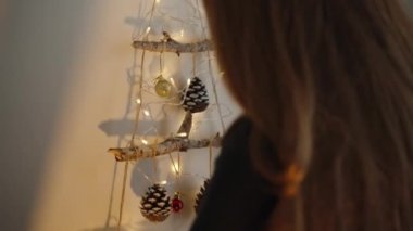 Genç bir kadın evi için Noel süslemeleri yapıyor..