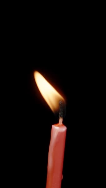 黑色背景上的红色蜡烛旋转 吹拂风并吹灭它 垂直录像 — 图库视频影像