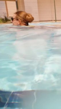 Yüzme havuzu ve su altında kamera. Sarı mayolu genç bir kadın, dikey, sosyal medya.