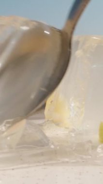 Limon dilimli bir tabakta limon jölesi. Onu bir kaşıkla parçalara ayırıyorum. Dikey, Sosyal Ortam.