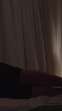 Geceleri, genç kadın yastığa uzanır ve telefonu tutar. Dikey, Sosyal Ortam.