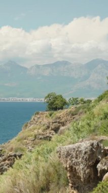 Deniz manzarası, dağlar ve şehir yüksek bir uçurumdan. Suda bir tekne. Dikey, Sosyal Ortam.