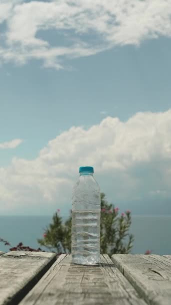 Een Fles Water Een Houten Tafel Uitzicht Zee Wolken Bomen — Stockvideo