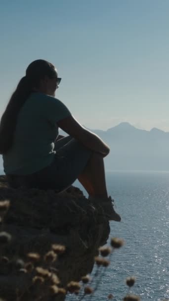 若い女性は崖の端に立っている ソーシャルメディアの山々を称賛する — ストック動画