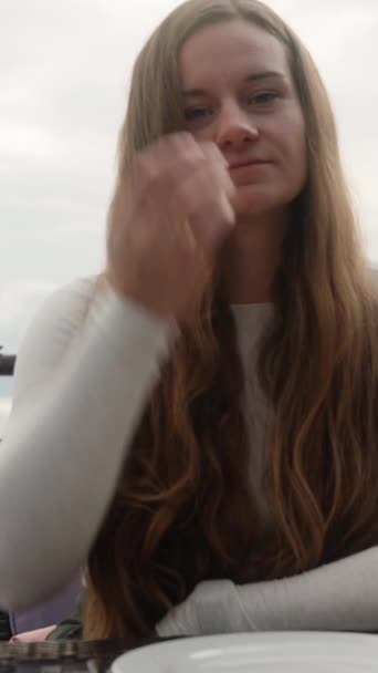 一个在海边悬崖边的餐馆里的年轻女人 多云的天气 垂直视频社交媒体 — 图库视频影像