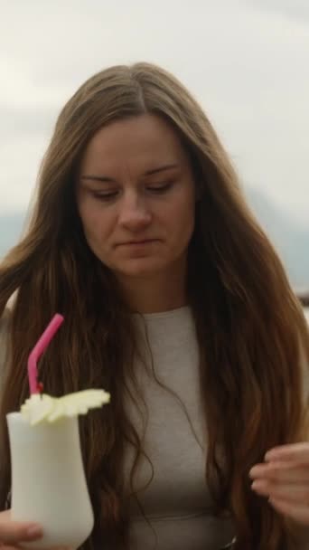 一位年轻女子在海边山上的一家餐馆里喝着鸡尾酒 垂直视频社交媒体 — 图库视频影像