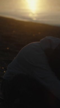 Sabahın köründe deniz kenarında genç bir kadın yoga minderinde meditasyon yapıyor..