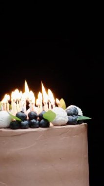 Yaban mersinli çikolatalı pasta ve yanan mumlar. Genç kadın mumları üflüyor. Dikey video Sosyal Ortamı.