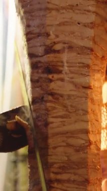Shawarma şiş üzerinde büyük bir parça tavuk eti, bir adam büyük bir bıçakla kabuğu keser et ateşte kızarırken. Dikey video Sosyal Ortamı.