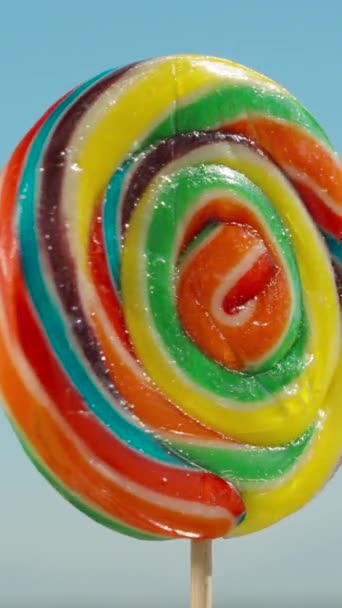 Multicolored Lollipop Stick Rotating Blue Sky Background Close Vertical Social — Stock Video