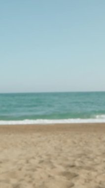 Genç kadın sahilde burnunu güneş kremiyle boyuyor. Deniz bardaklara yansıyor. Kum. Büyük dalgalar. - Dolly. Dikey. Sosyal Medya