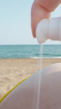 Sarı mayolu genç bir kadın göğsüne güneş kremi sürüyor. Deniz manzaralı. Dolly Dikey. Sosyal Medya