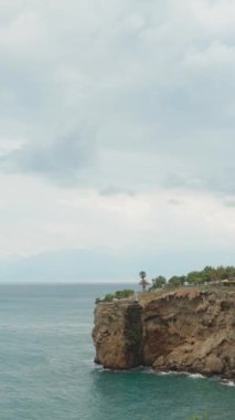 Dikey. Deniz kıyısındaki yüksek bir kayanın üzerinde büyük bir Türkiye bayrağı. Deniz manzaralı. Antalya