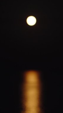 Çilekli süper ay denizin üstünde. Suda yansıma. Tekne ay ışığında dikey olarak hareket eder. Sosyal Medya