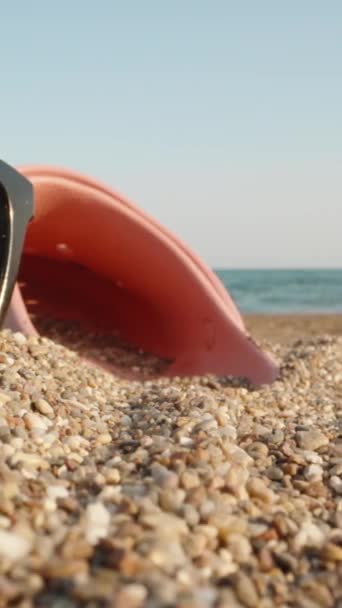 Zonnebrillen Roze Teenslippers Liggen Tegen Achtergrond Van Zee Het Zand — Stockvideo