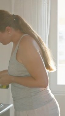 Yemek pişirmek. Yağı kızartma tavasına döküyorum. Pencerede güneş ışığı var. Hareket halinde. Dikey. Sosyal Medya