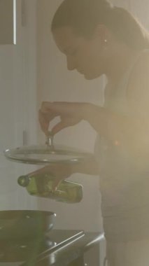 Yemek pişirmek. Yağı kızartma tavasına döküyorum. Pencerede güneş ışığı var. Hareket halinde. Dikey. Sosyal Medya