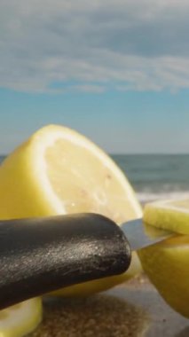 Kamera bir bıçak ve bir dilim limon üzerinde süzülür, arka plandaki deniz. Dikey. Sosyal Medya