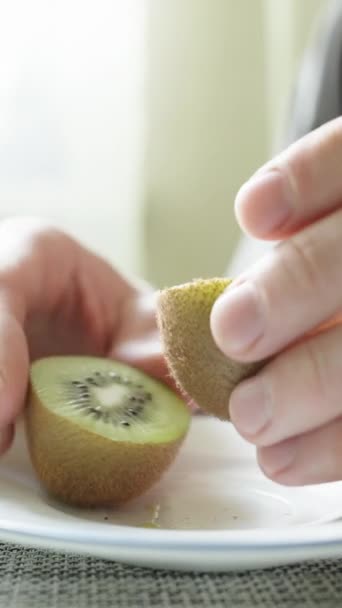 Een Man Snijdt Eet Een Kiwi Fruit Met Een Lepel — Stockvideo