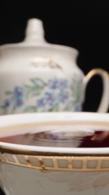Çay partisi, bir fincan çaya bir parça şeker atıyorum, sıçrıyor. Ağır çekim, Dolly kaydırıcı aşırı yakın çekim. Laowa Sondası Dikey Video.