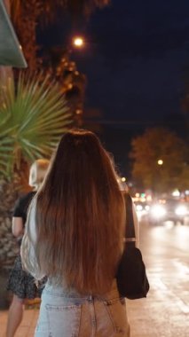 Arabalı gece yolu. Duraktaki genç bir kadın otobüsü durdurmak için elini kaldırır. Spa şehri, yaz dikey video.