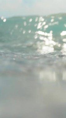 Kamera bir deniz dalgası ile kaplıdır. Su altında taşlar. Dikey video.
